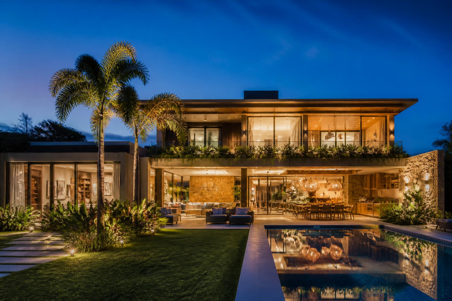 Casa moderna iluminada ao anoitecer, com jardim e piscina