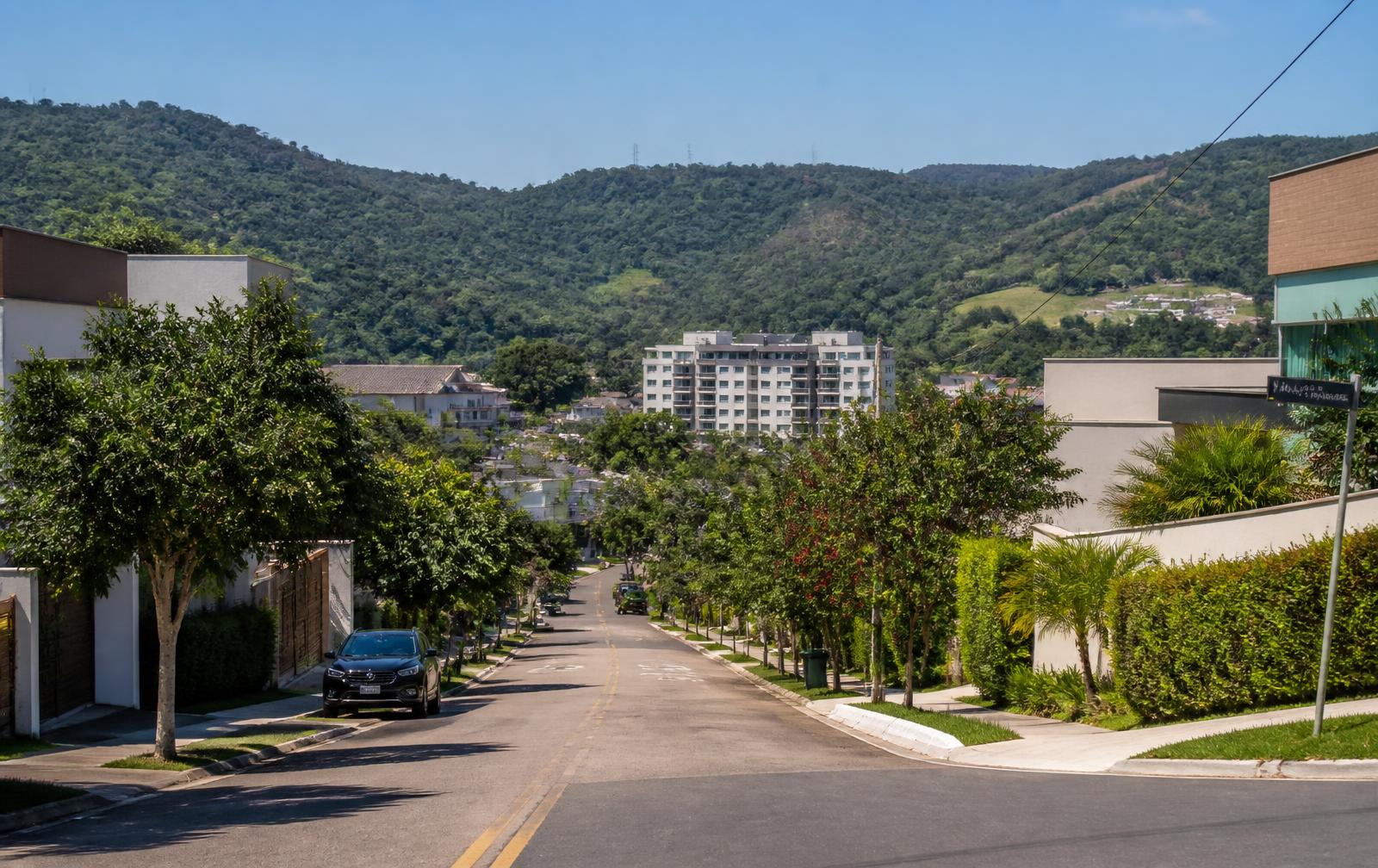 Rua residencial arborizada no bairro Anhangabaú, em Jundiaí, com morros ao fundo
