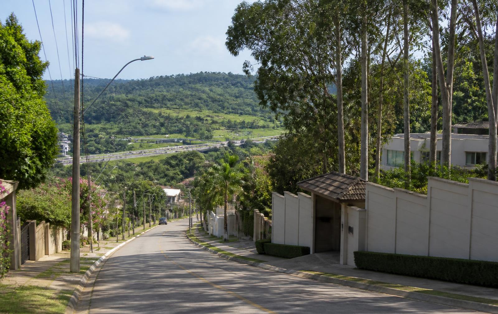 Avenida residencial do bairro Engordadouro, em Jundiaí, com muros de condomínios e árvores altas